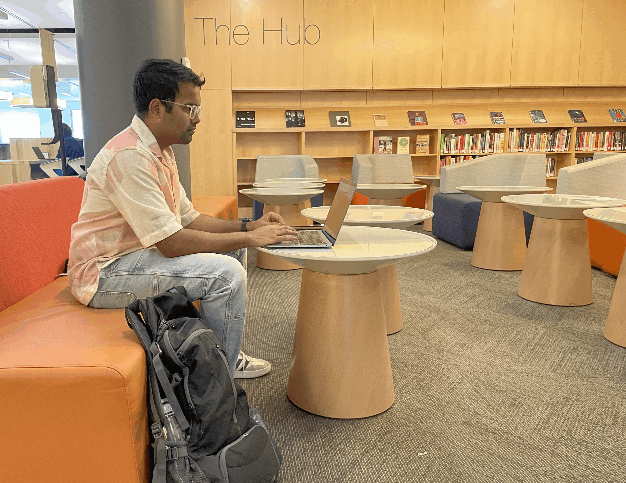 Student working on a laptop computer while seated in the area of the first floor of Snell Library called The Hub.